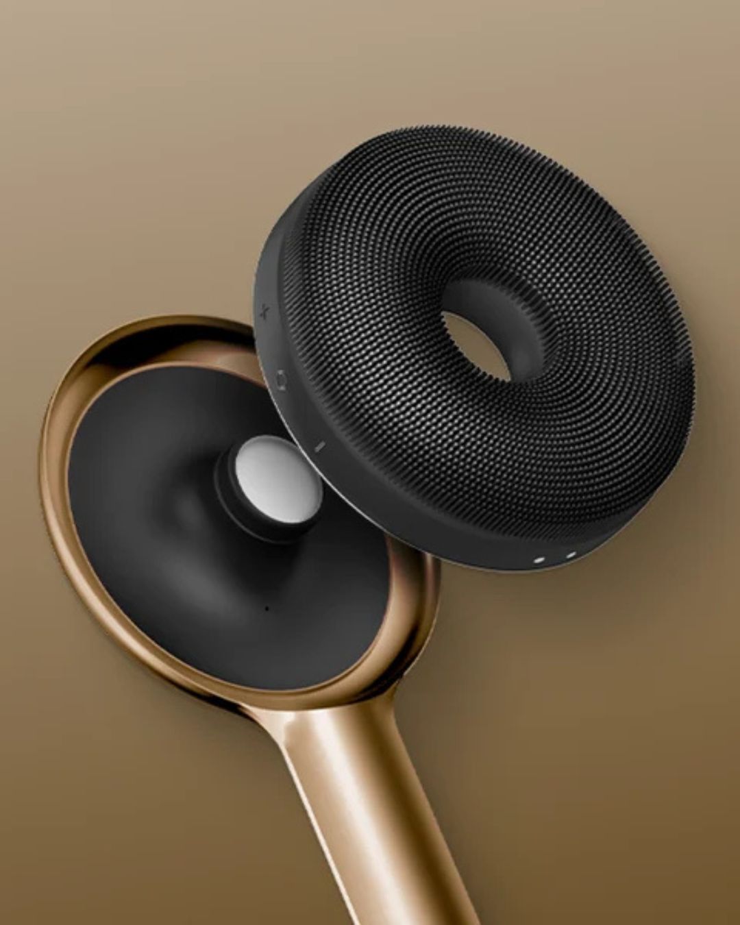 Close-up of GESKE black circular silicone brush head with fine bristles next to gold handle